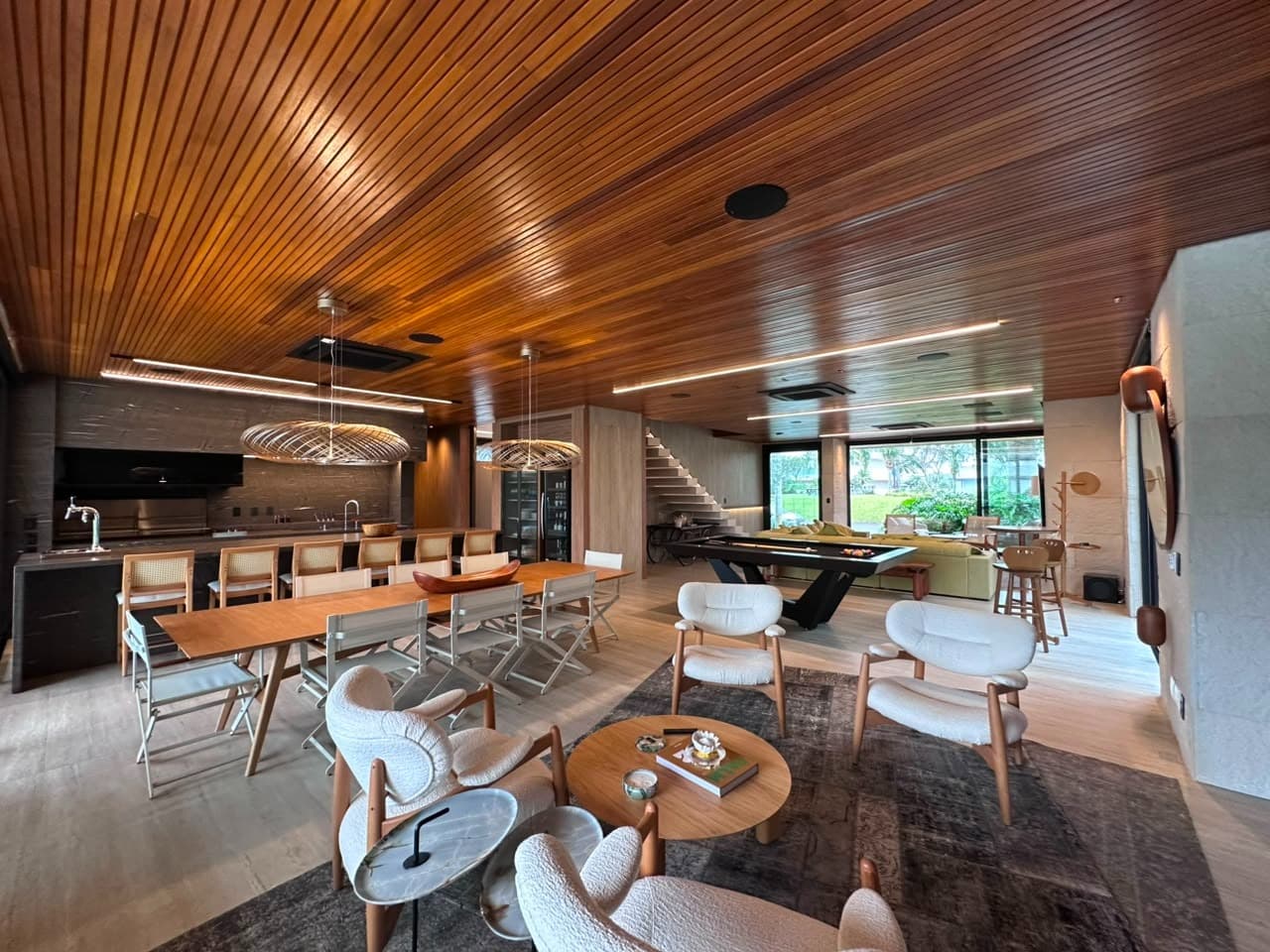 Living e sala de jantar integrados da Casa Enseada, com forro em madeira