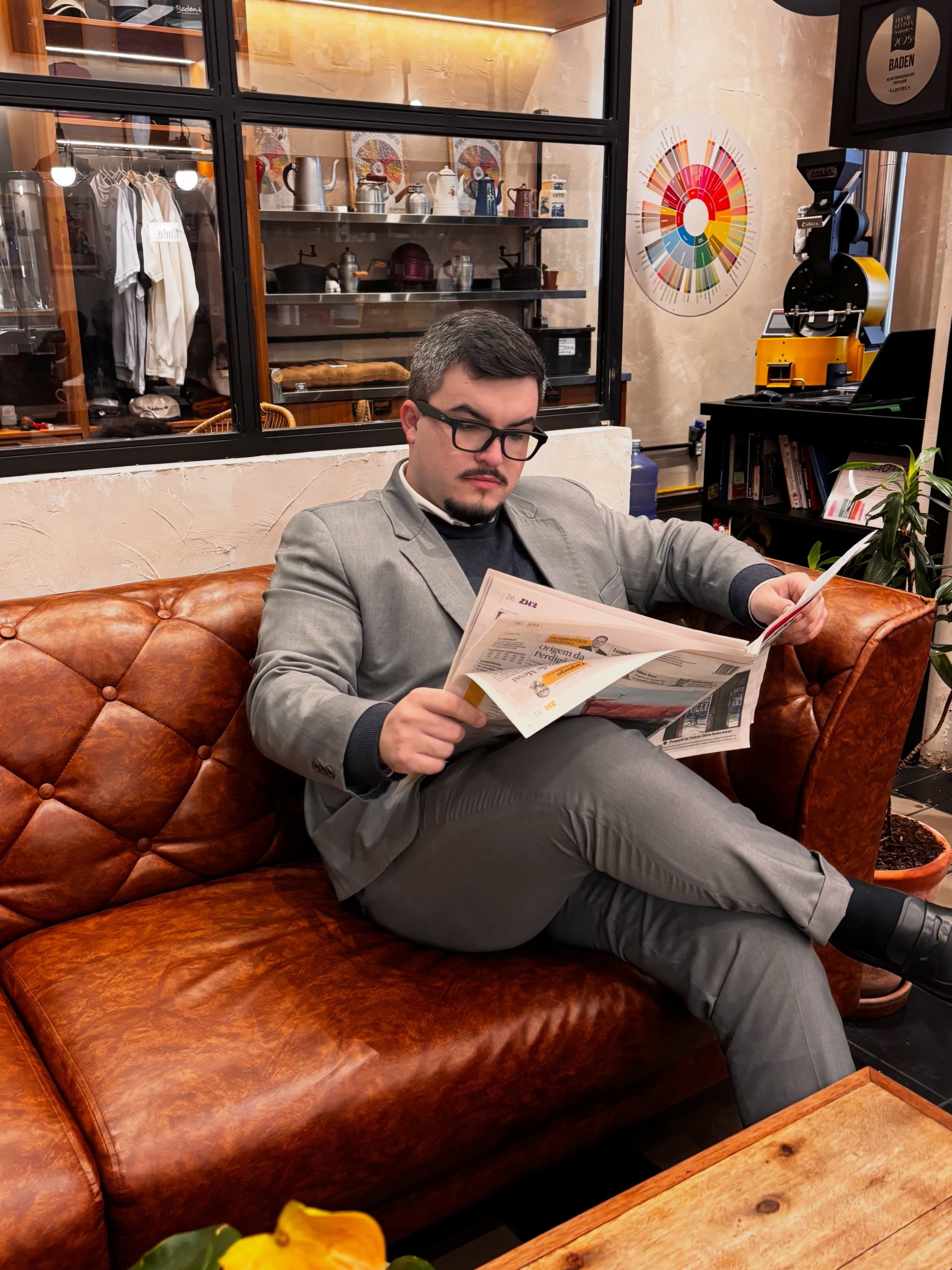 João Martinelli sentado, lendo jornal, em uma cafeteria